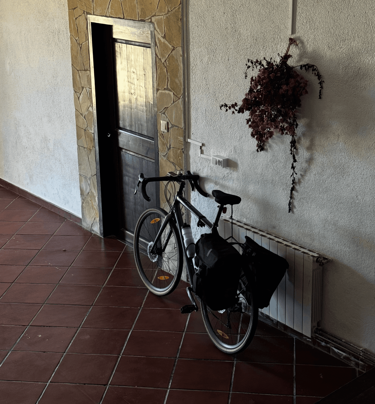 A loaded gravel bike leaning against a wall